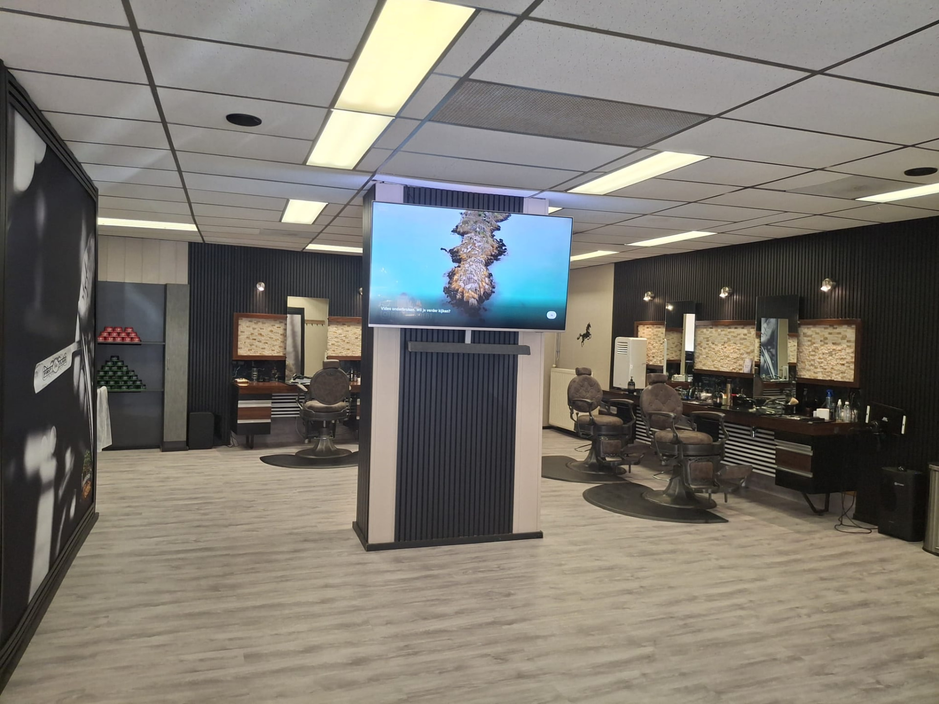Overzicht van de barbershop met tv en werkplekken
